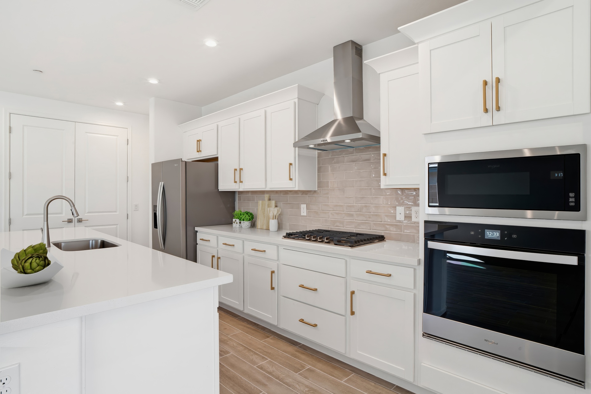 spacious kitchen with white cabinets, brushed gold hardware, and a gourmet kitchen