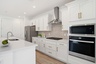 spacious kitchen with white cabinets, brushed gold hardware, and a gourmet kitchen