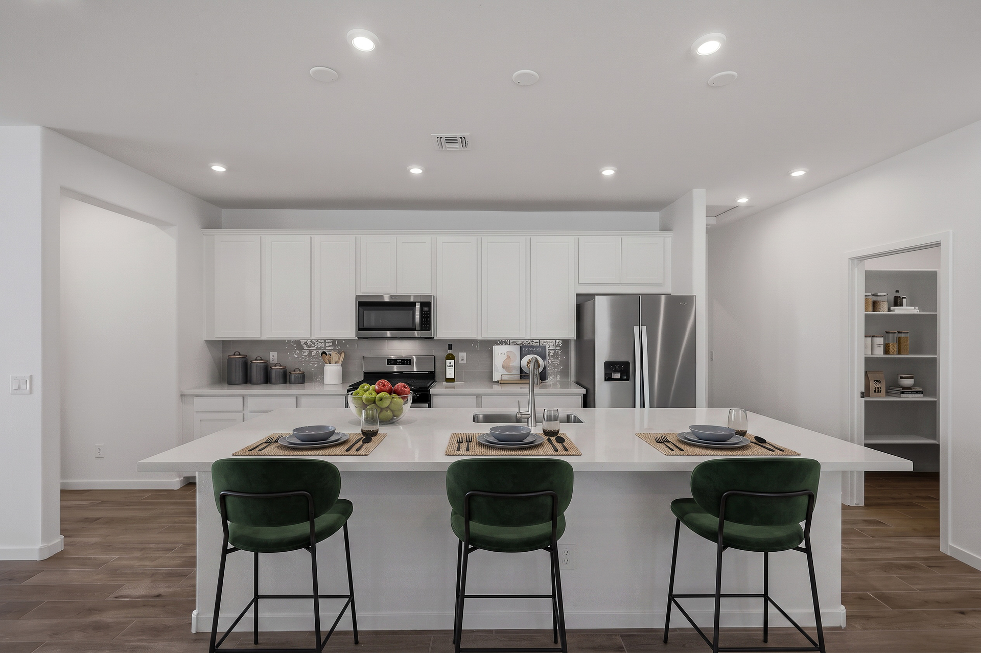 open-concept kitchen with white cabinets, quartz countertops, and green barstools