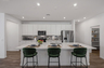 open-concept kitchen with white cabinets, quartz countertops, and green barstools