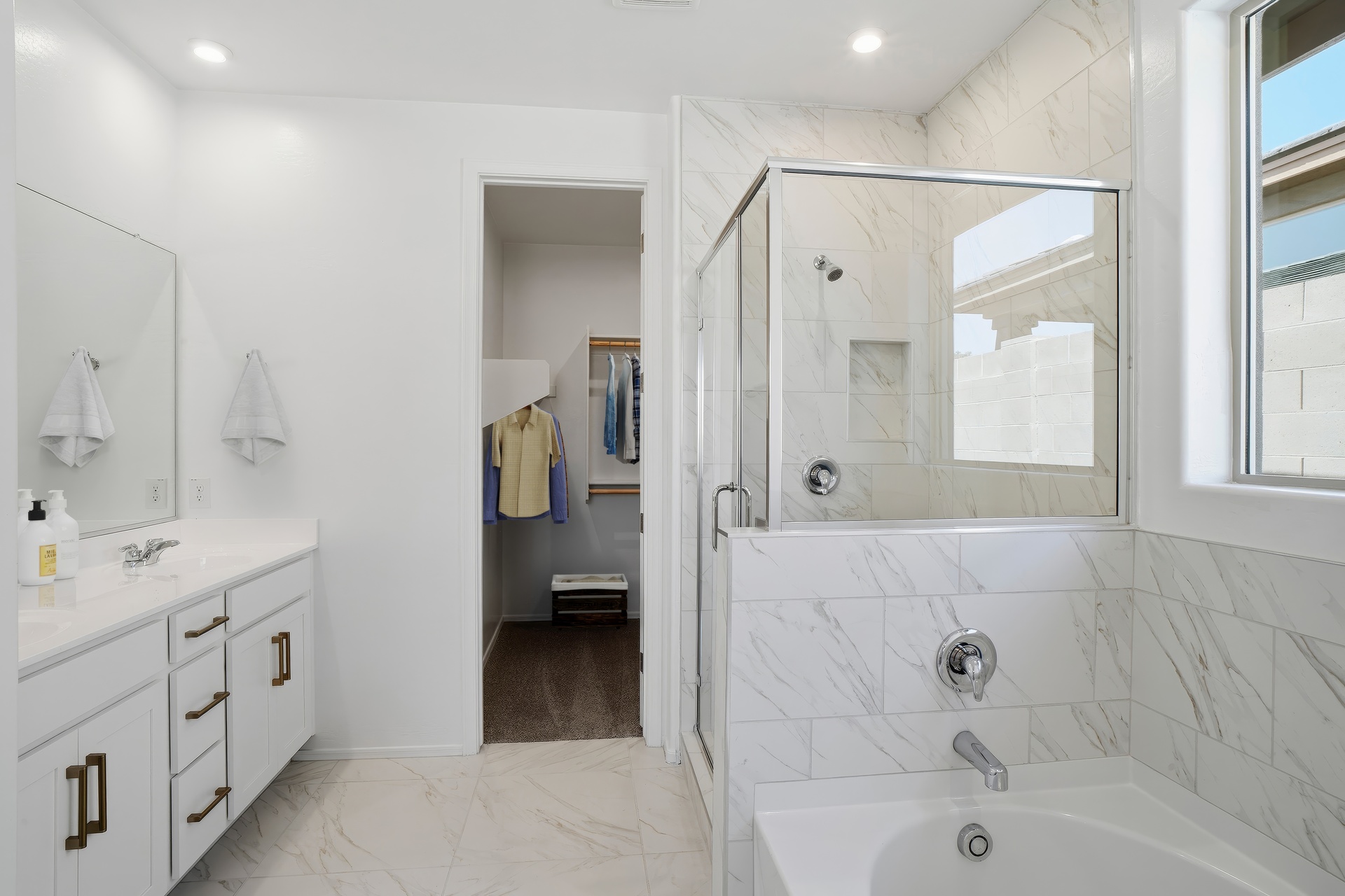 spacious bathroom with a walk-in shower, a soaking tub, and white cabinets