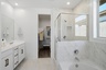 spacious bathroom with a walk-in shower, a soaking tub, and white cabinets