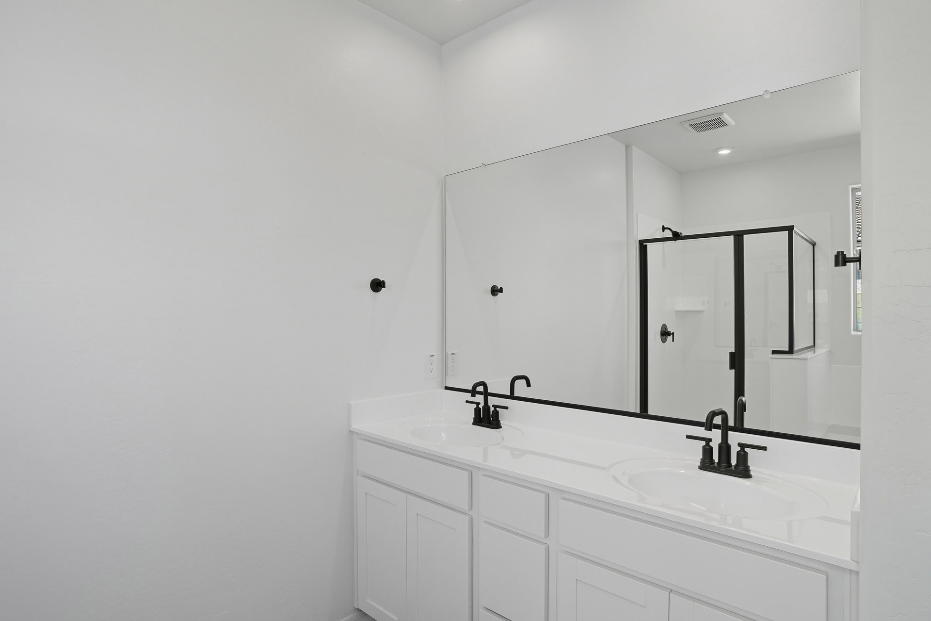 spacious bathroom with white cabinets, white countertops, and black hardware