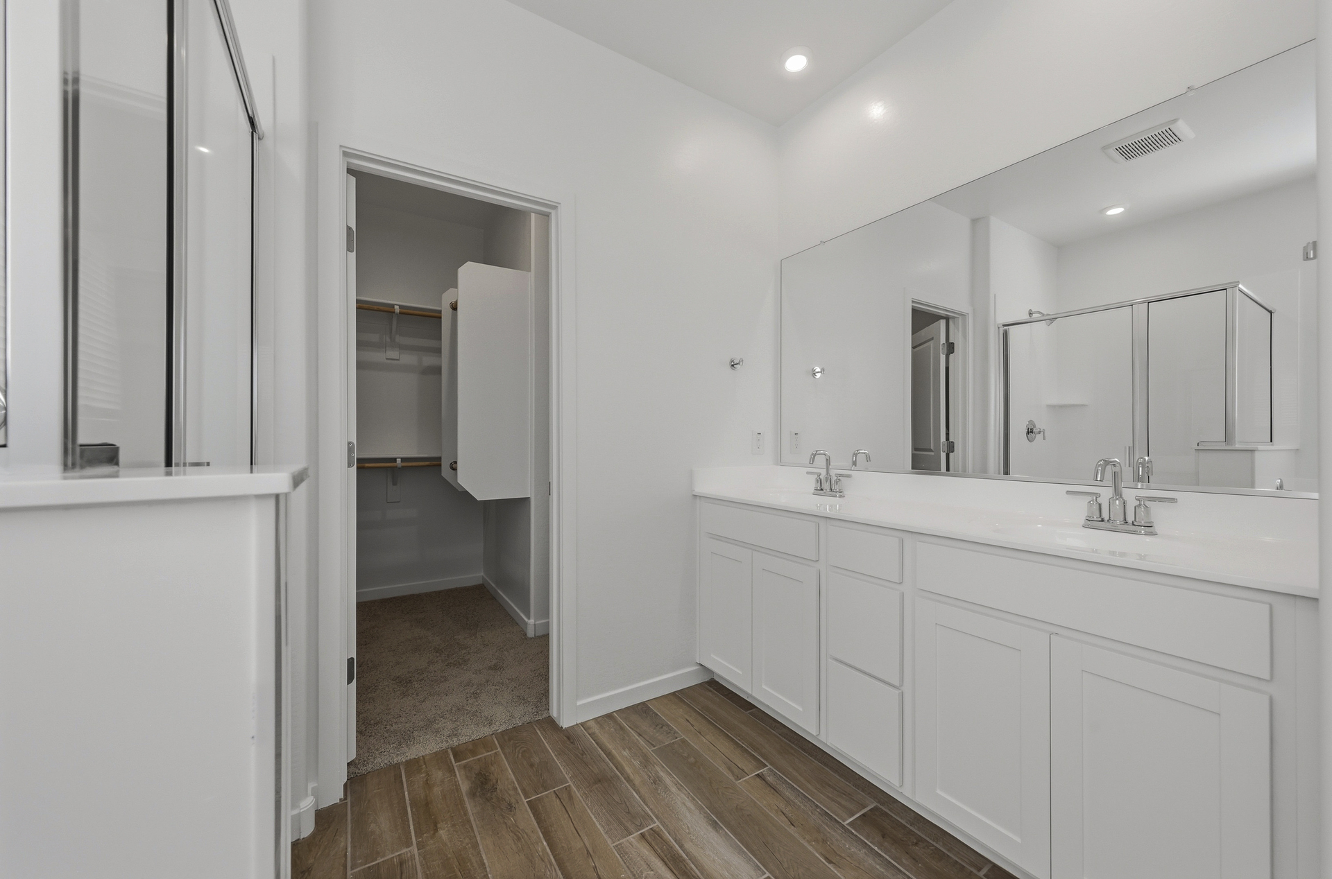 spacious bathroom with white cabinets, a double sink, and chrome faucets