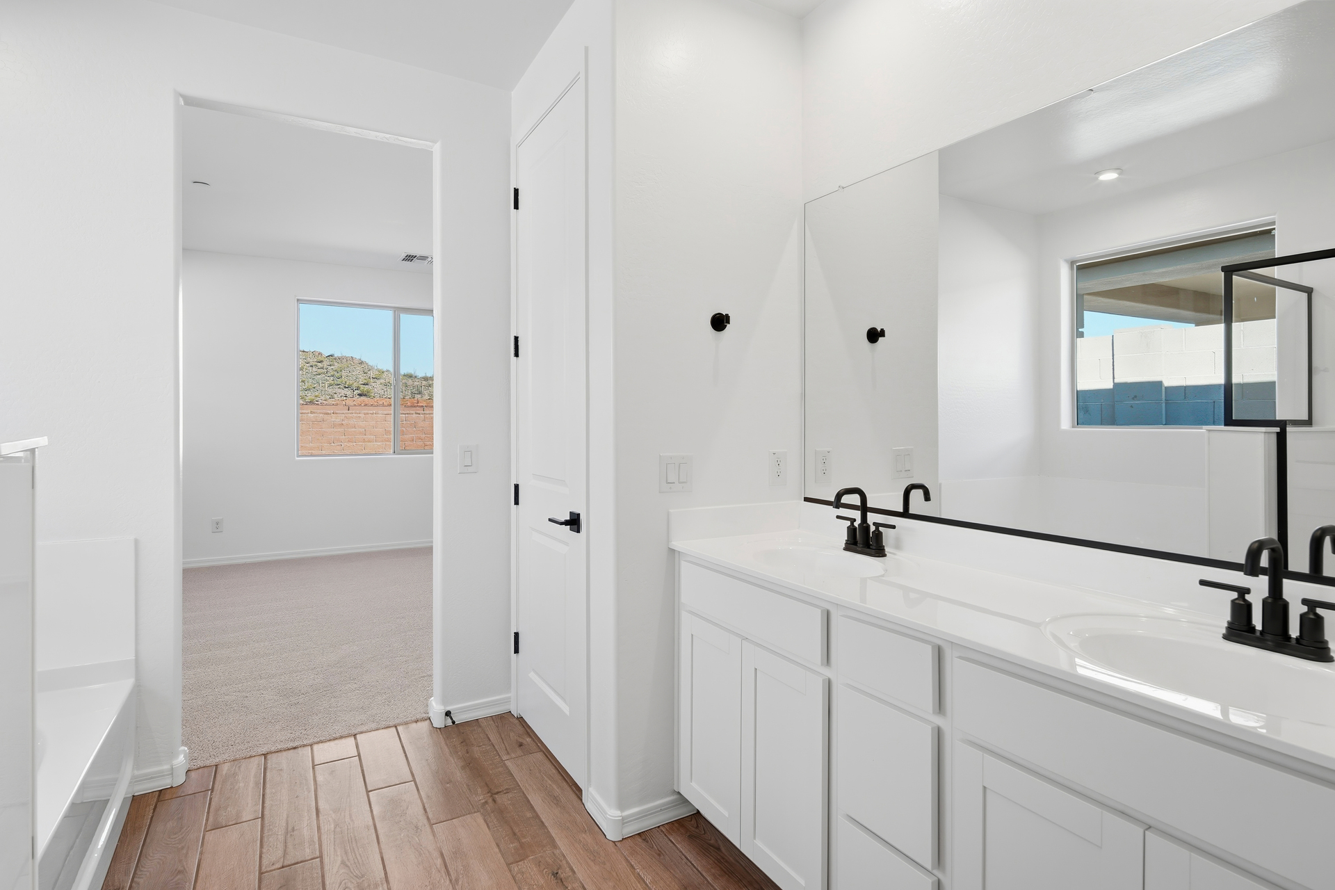bathroom with wood-like flooring, white cabinets, and black faucets