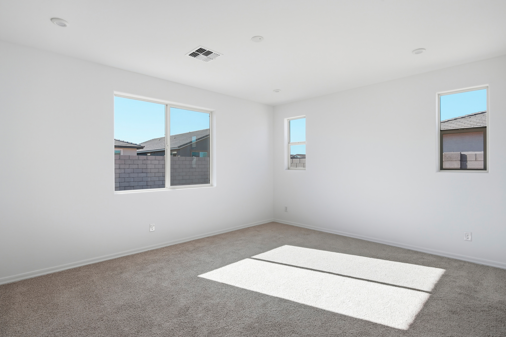 spacious bedroom with light brown carpet and windows for natural light