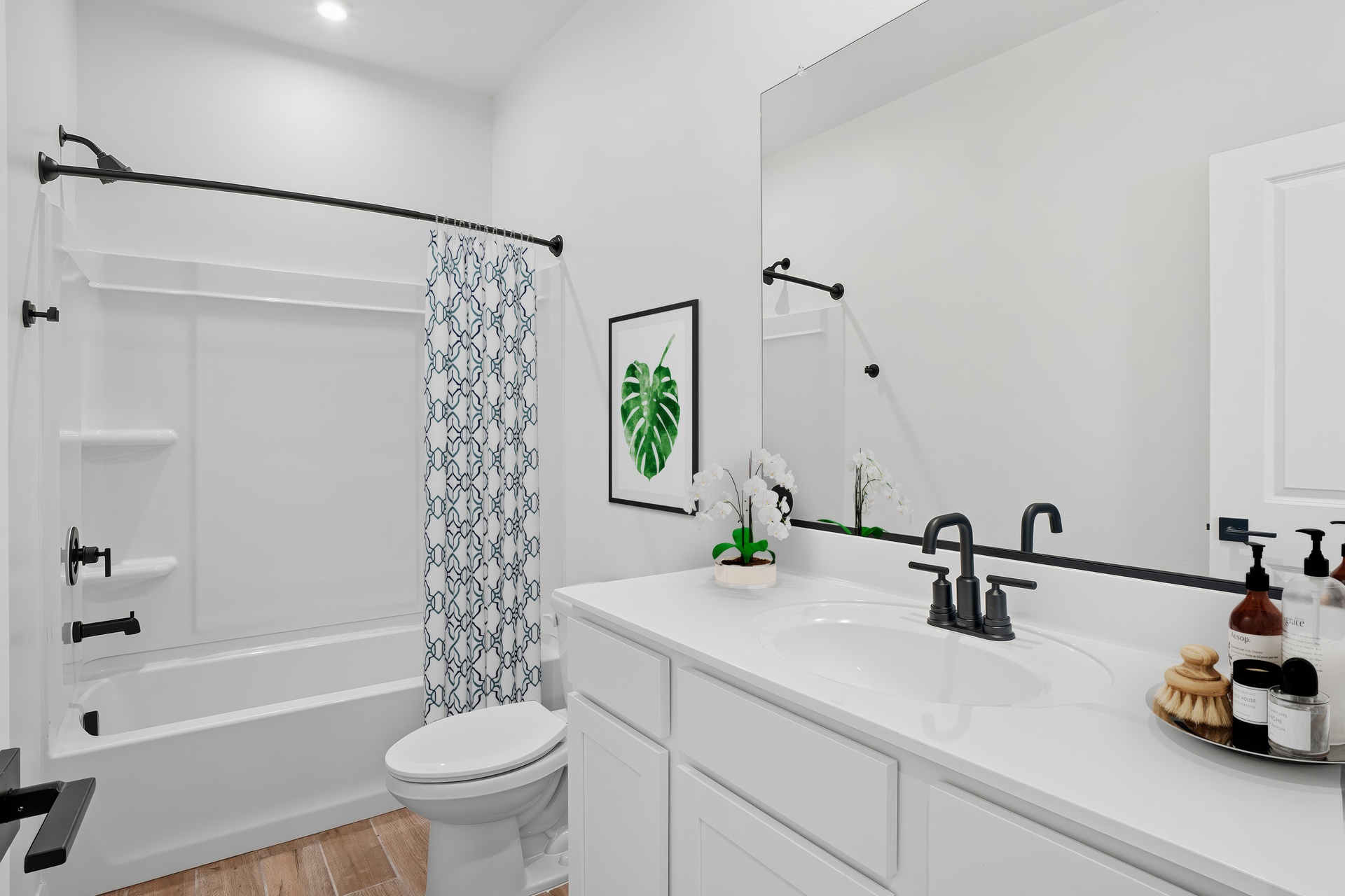 bathroom with white cabinets, white countertops, and black hardware