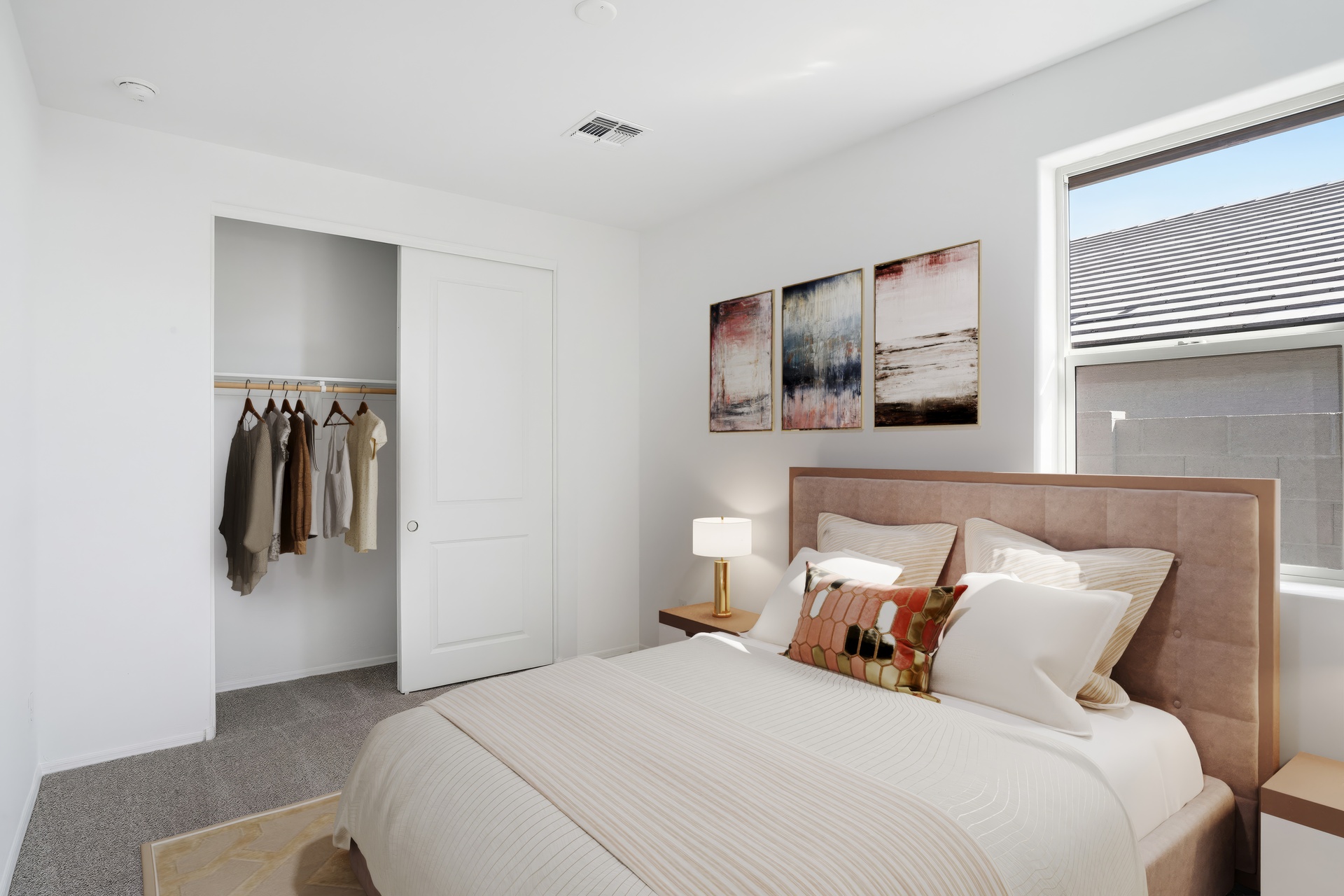 large bed with light beige bedcovers, beige rug, and wooden nightstands