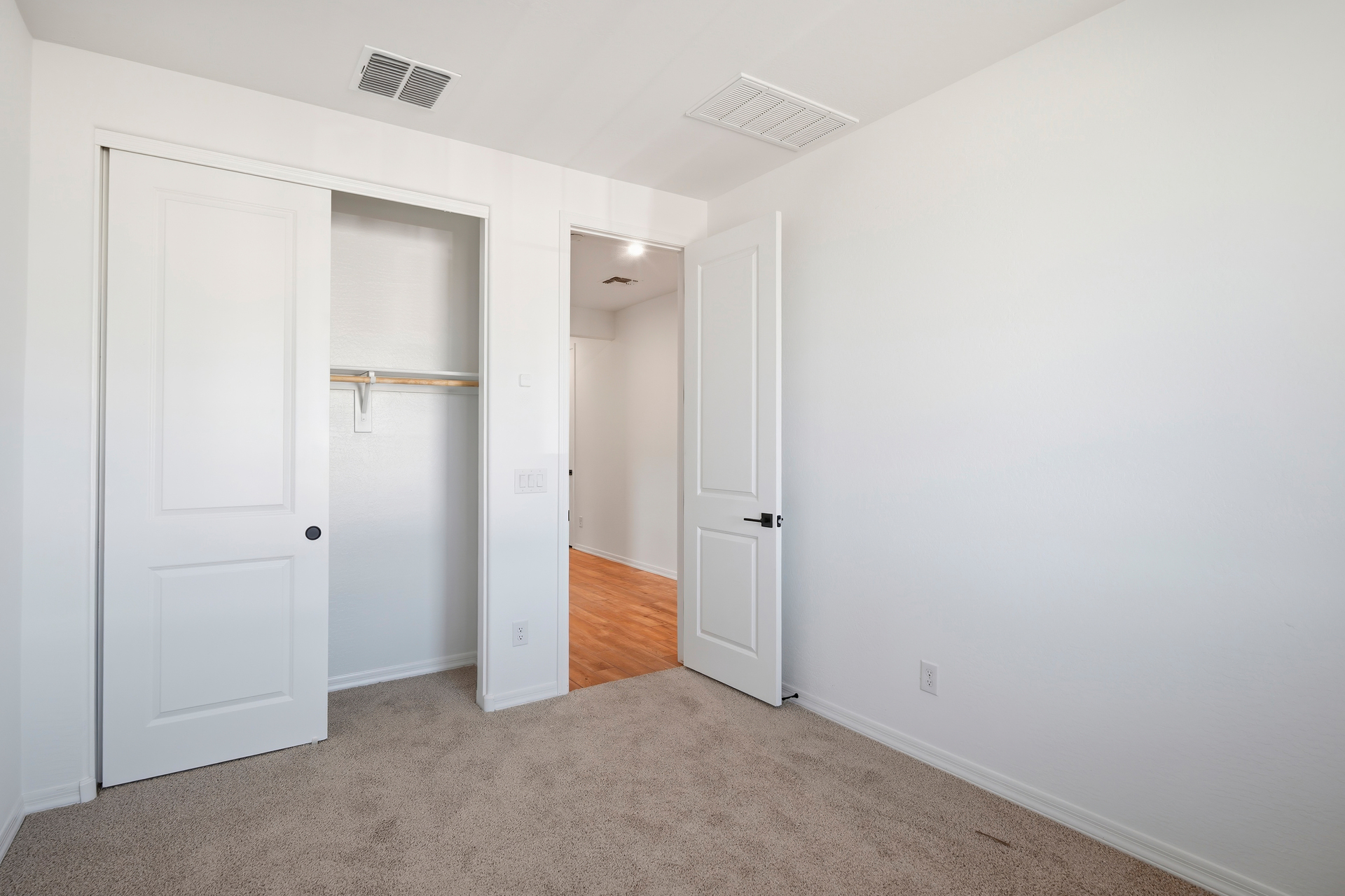 spacious bedroom with light brown carpet and closet with sliding door