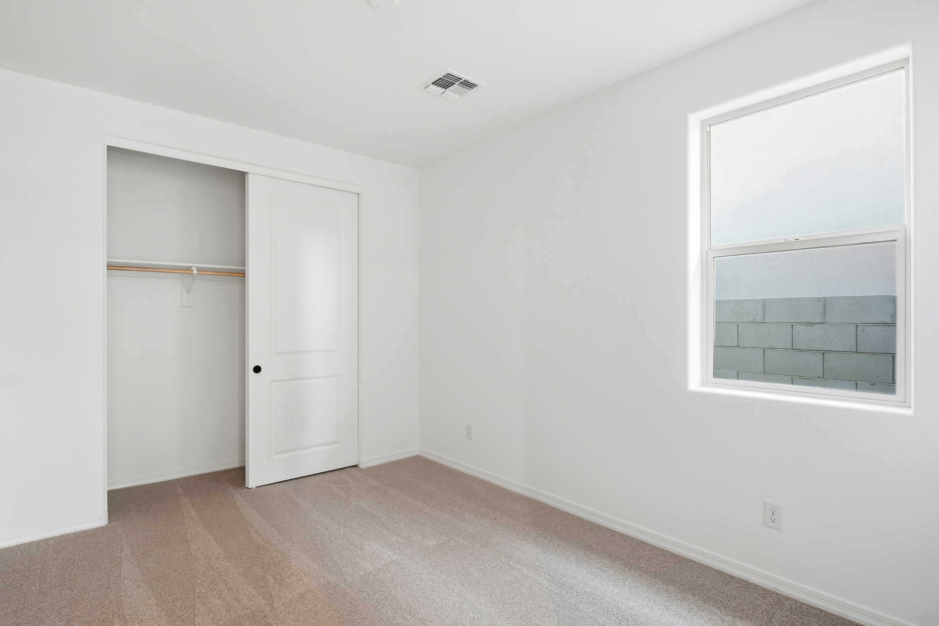 bedroom with light brown carpet and window for natural light
