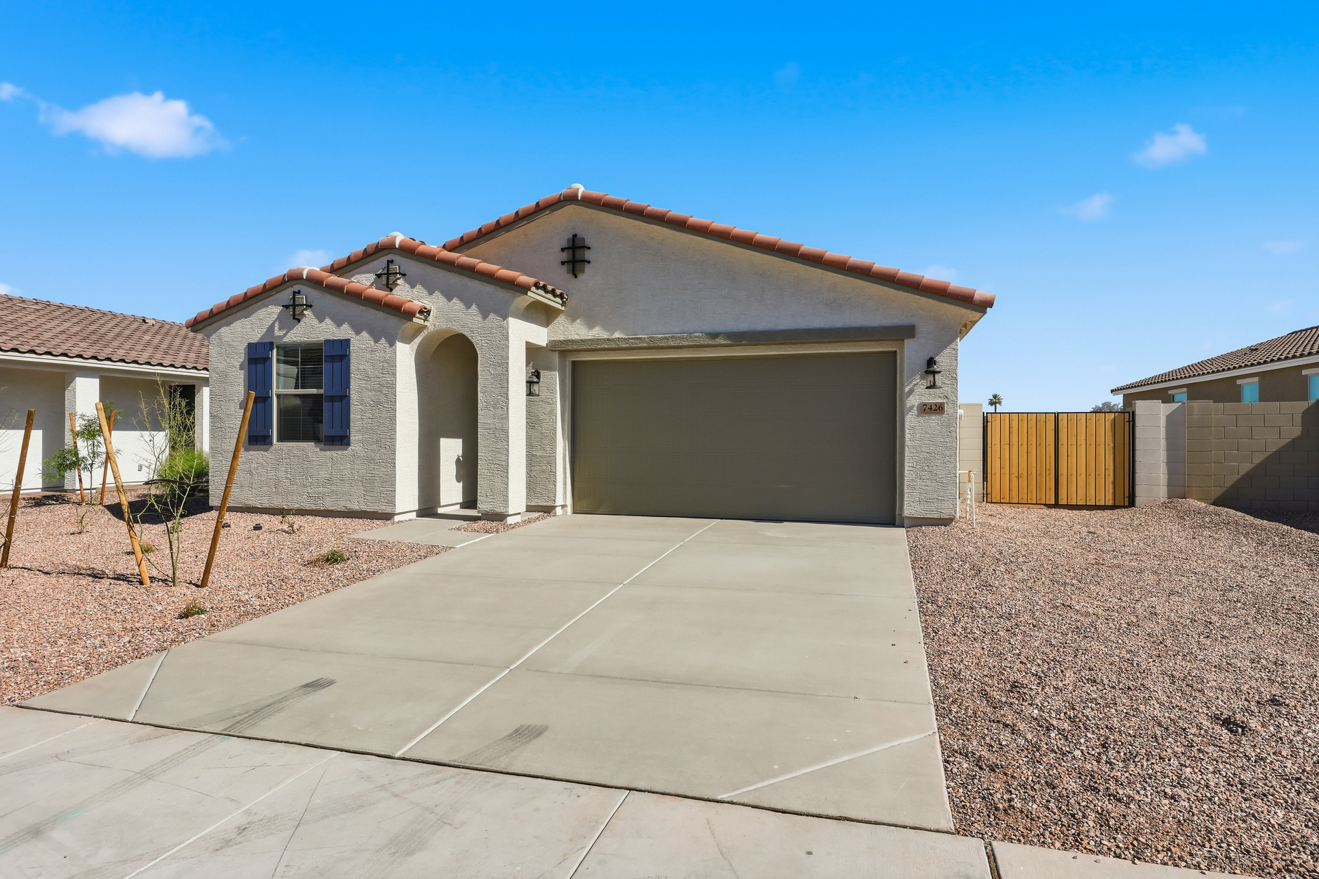 single-story single-family home with desert landscaping, a double gate, and a concrete driveway
