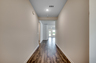 welcoming hallway with tan walls, puck lighting and hardwood flooring throughout