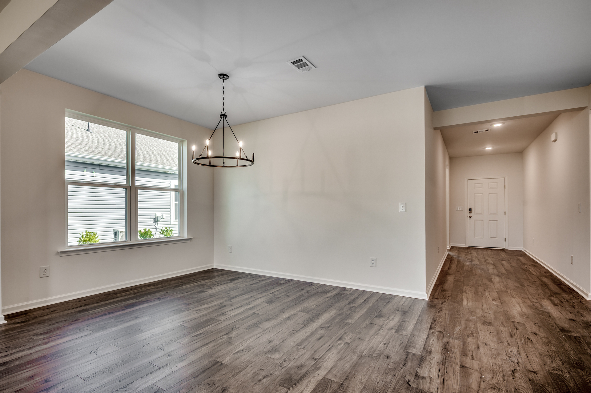 spacious eating area with large windows, tan walls and black pendant lighting 