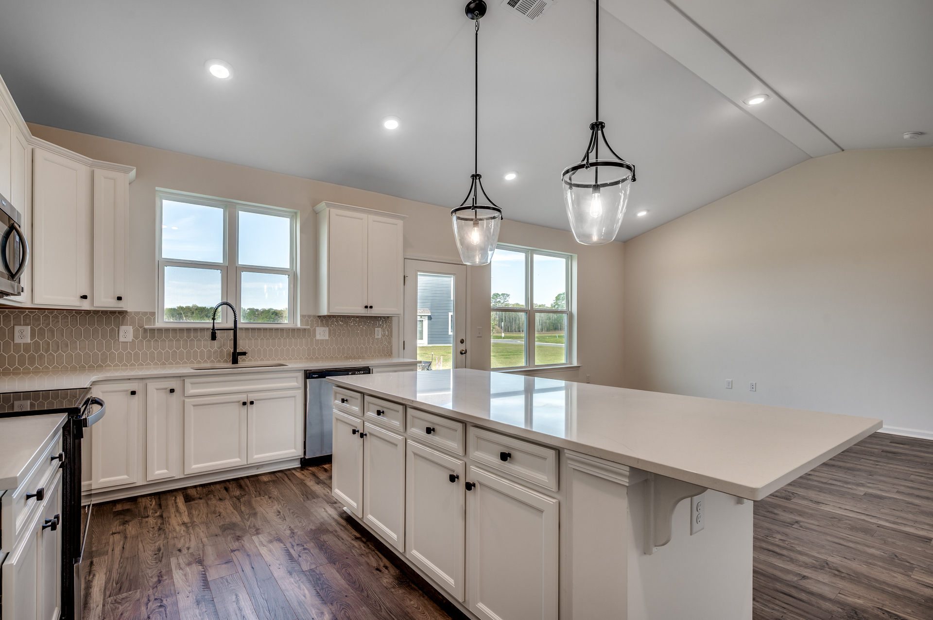 bright white cabinets with tan backsplash and black pendant lighting