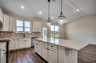 bright white cabinets with tan backsplash and black pendant lighting