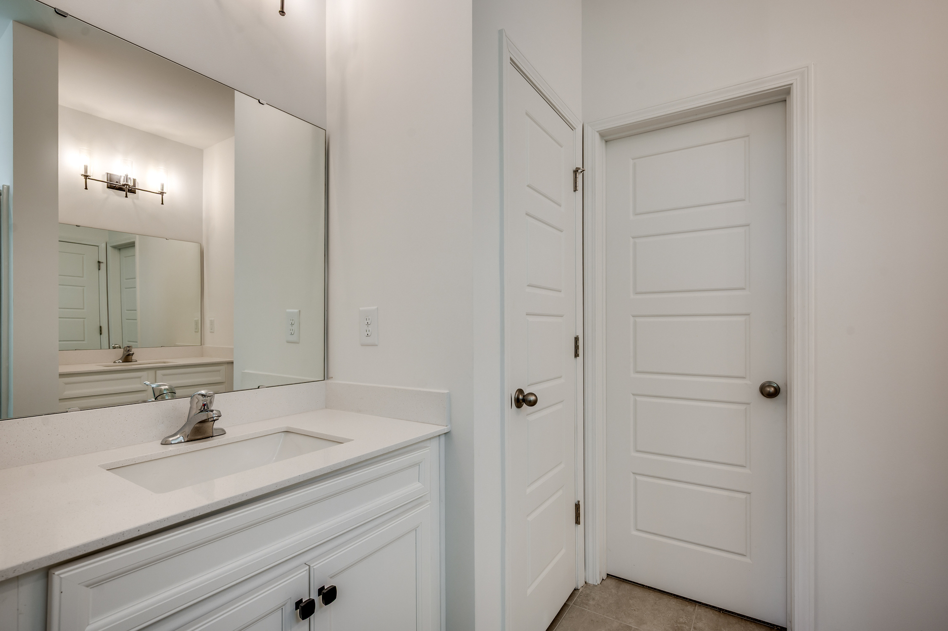 bright white single sink vanity with silver faucet and black hardware