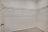 spacious area for extra storage with white wire built-in shelving and carpeting
