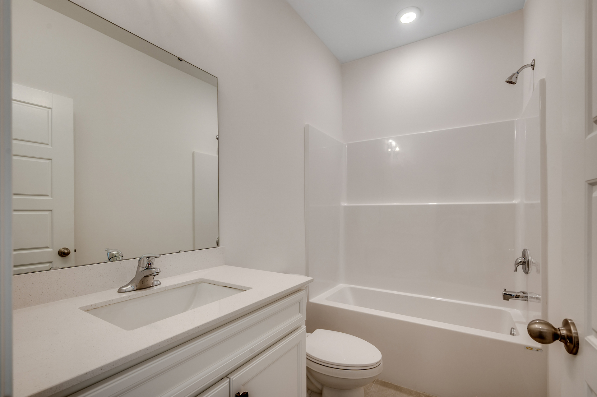 bright white room with single sink vanity, large mirror and spacious shower