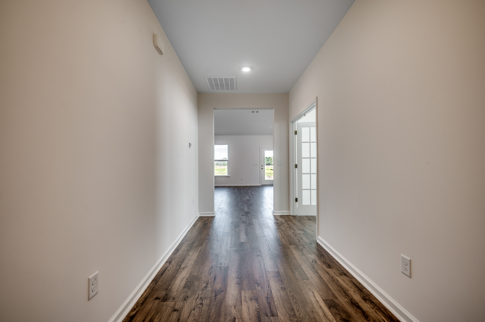 welcoming entryway with tan walls, white base boards and hardwood flooring throughout