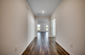 welcoming entryway with tan walls, white base boards and hardwood flooring throughout