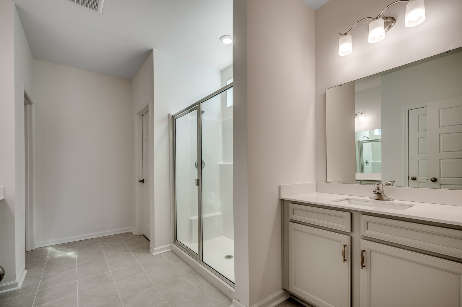large single sink vanity with gray cabinets, gold hardware and tile flooring throughout