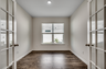 large windows for natural light, hardwood flooring and glass french doors 