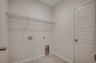spacious room with tan walls, white wire built in shelving and tile flooring 