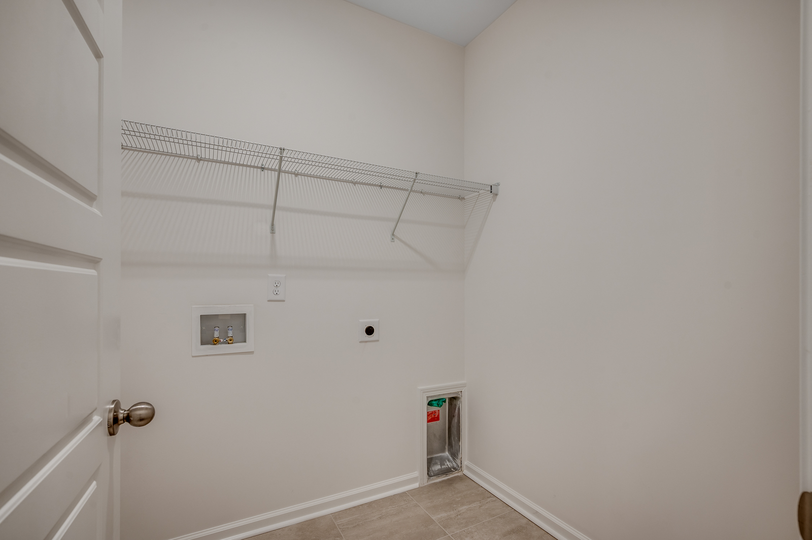 spacious room with white wire shelving, tan walls and tile flooring