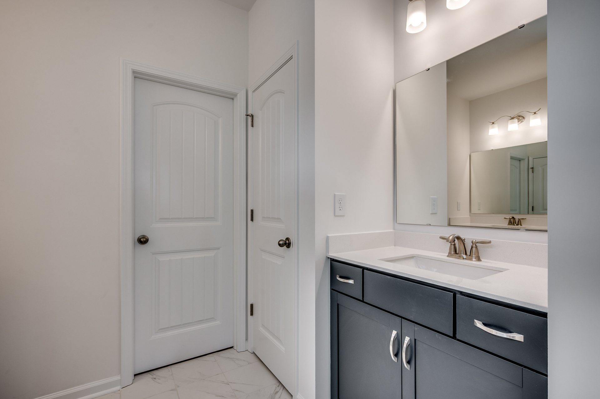 dark blue single sink vanity with large mirror and tile flooring
