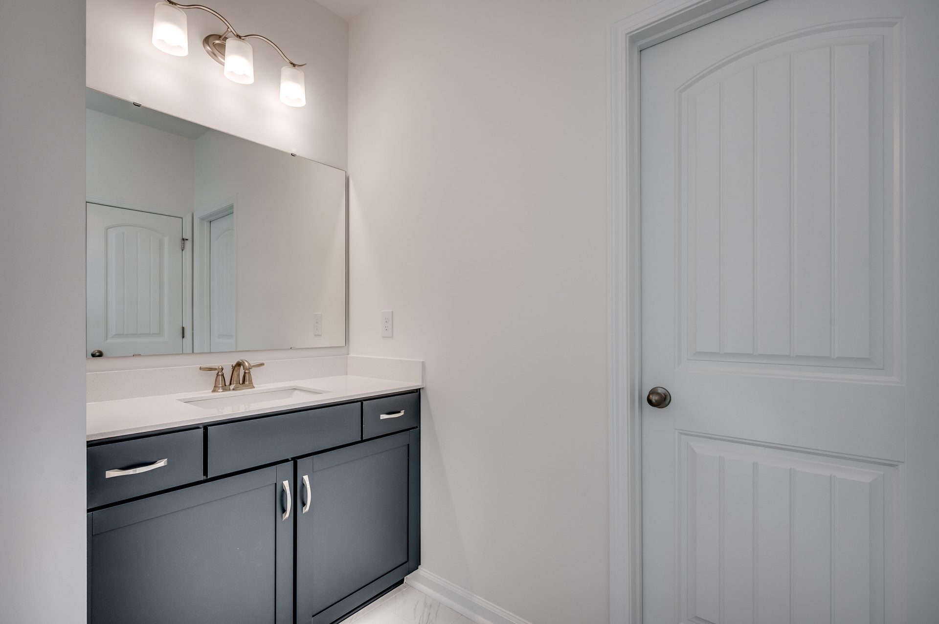 dark blue single sink vanity with large mirror and tile flooring