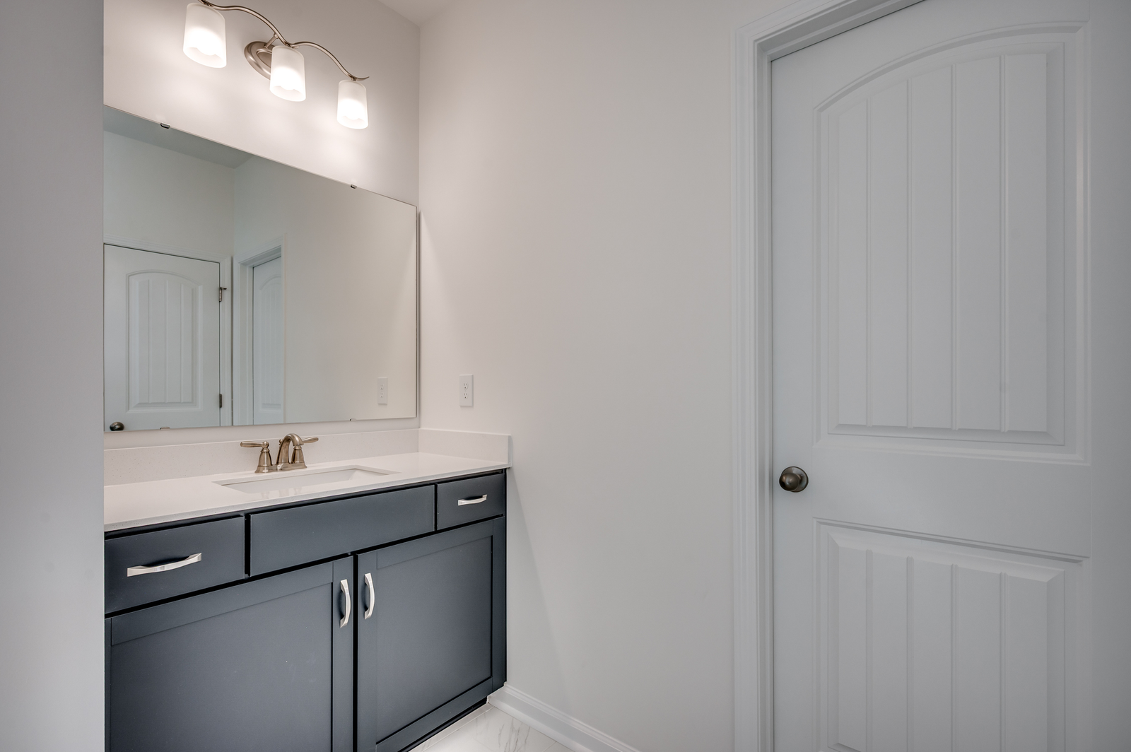 dark blue single sink vanity with large mirror and tile flooring