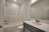 dark blue single sink vanity with large mirror and quartz countertops 