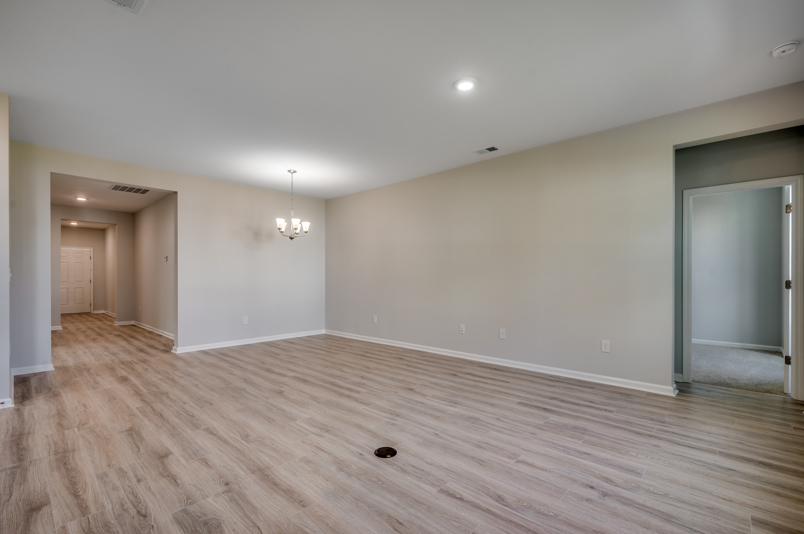 open-concept area with hardwood flooring, tan walls and chandelier