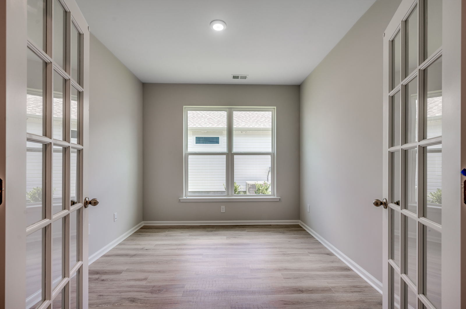 bright room with large windows, glass french doors and hardwood flooring