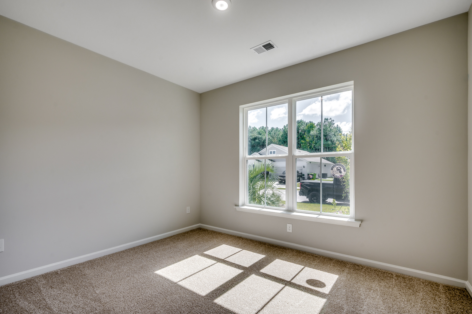 large windows for natural lighting, tan walls and carpet throughout