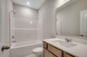 dark brown single sink vanity with large mirror and bright white shower