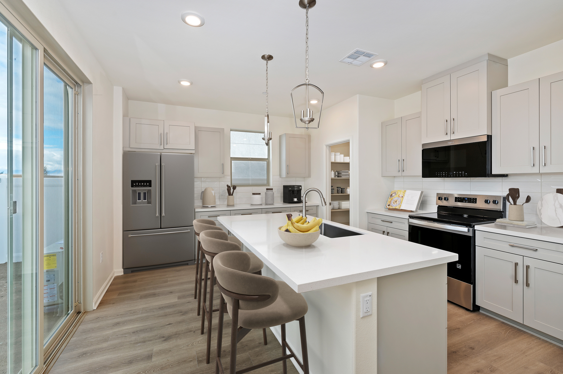 kitchen with a white island that has light brown bar stools and a stainless steel fridge