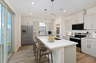 kitchen with a white island that has light brown bar stools and a stainless steel fridge