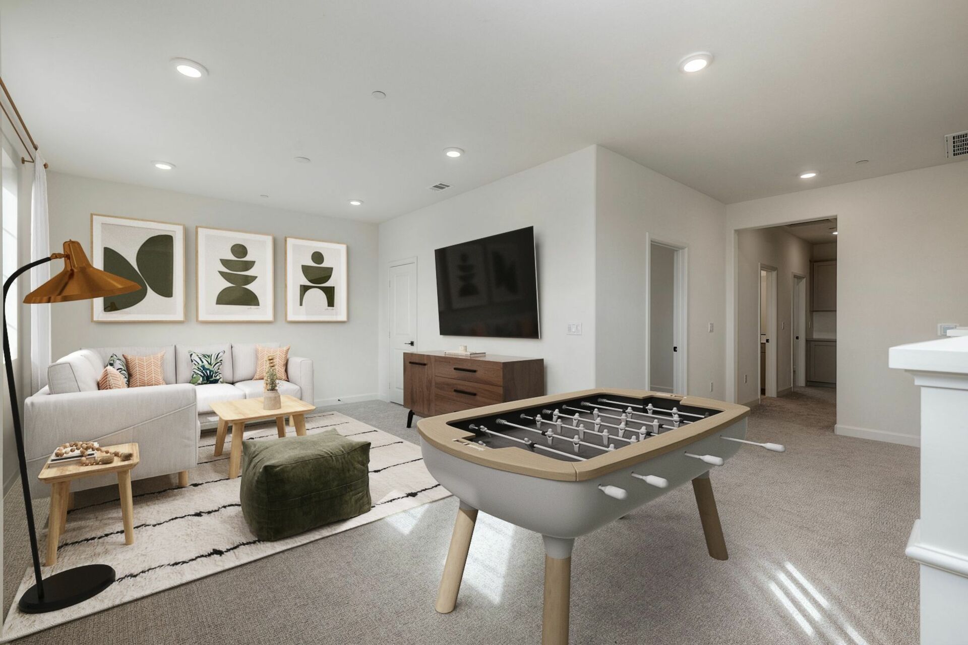loft with a small white sectional on top of a patterned rug and a fooseball table