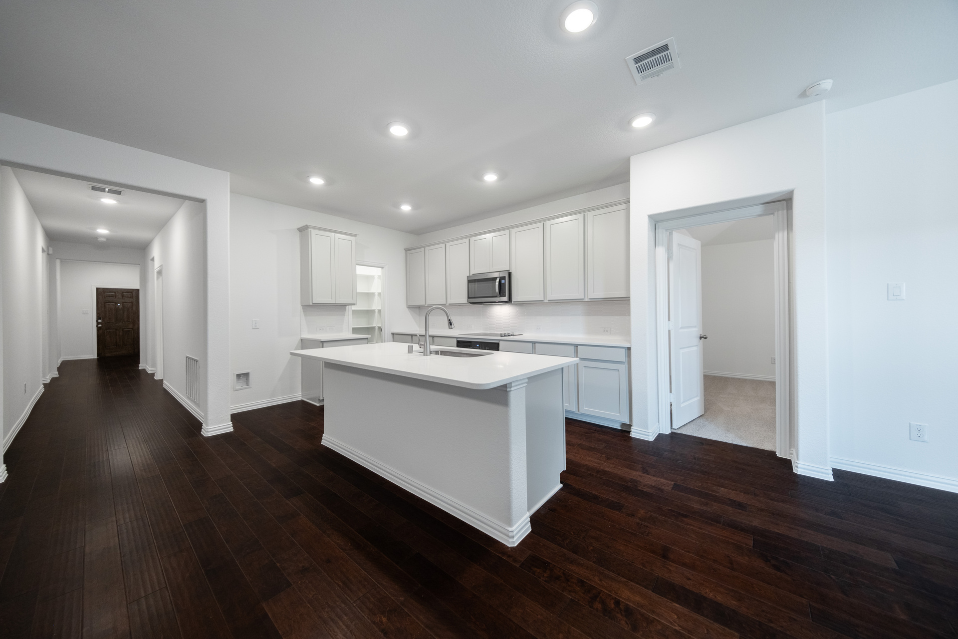 open kitchen with white countertops and hardwood flooring