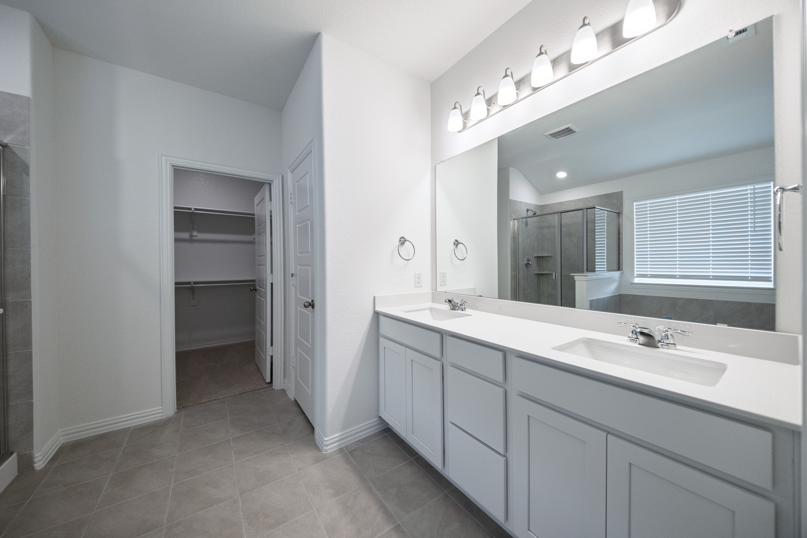 primary bathroom with tile flooring and double sinks