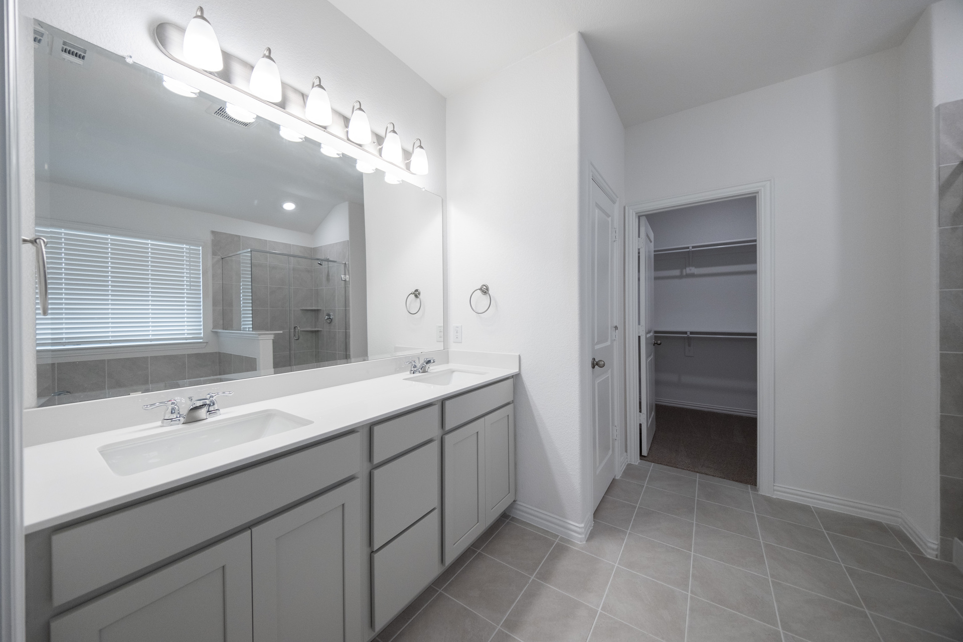 primary bathroom with tile flooring and double sinks