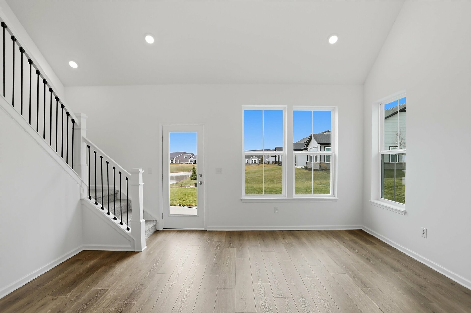 great room with open railing staircase and windows letting in natural light