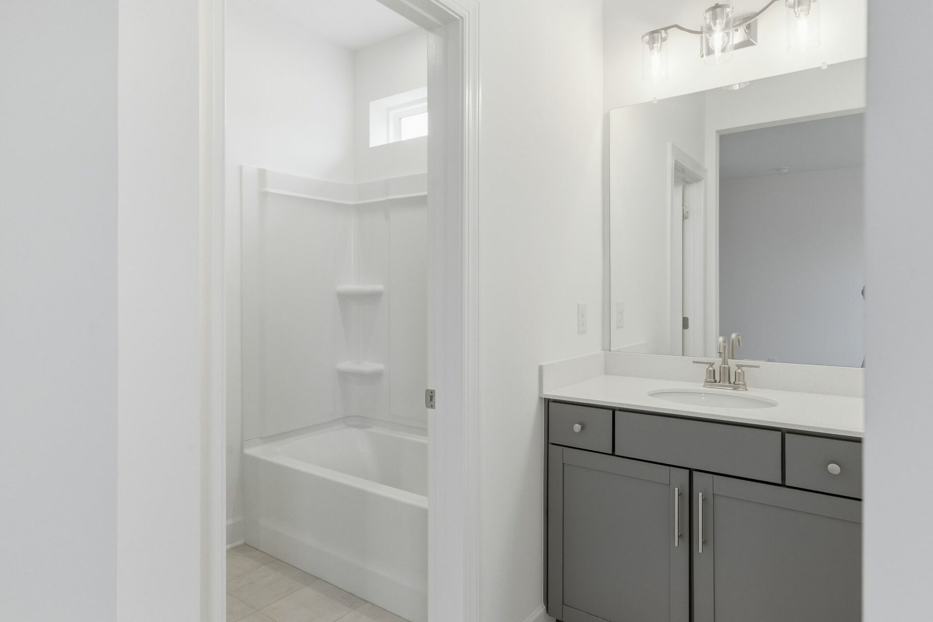 secondary bathroom with gray cabinets, white countertops, and a shower and tub combination