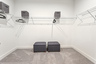 walk in closet with shelves and carpet