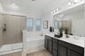 primary bathroom with double sink vanity, glass walk-in shower, and a large soaking tub
