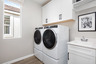 laundry room with neutral floors and storage