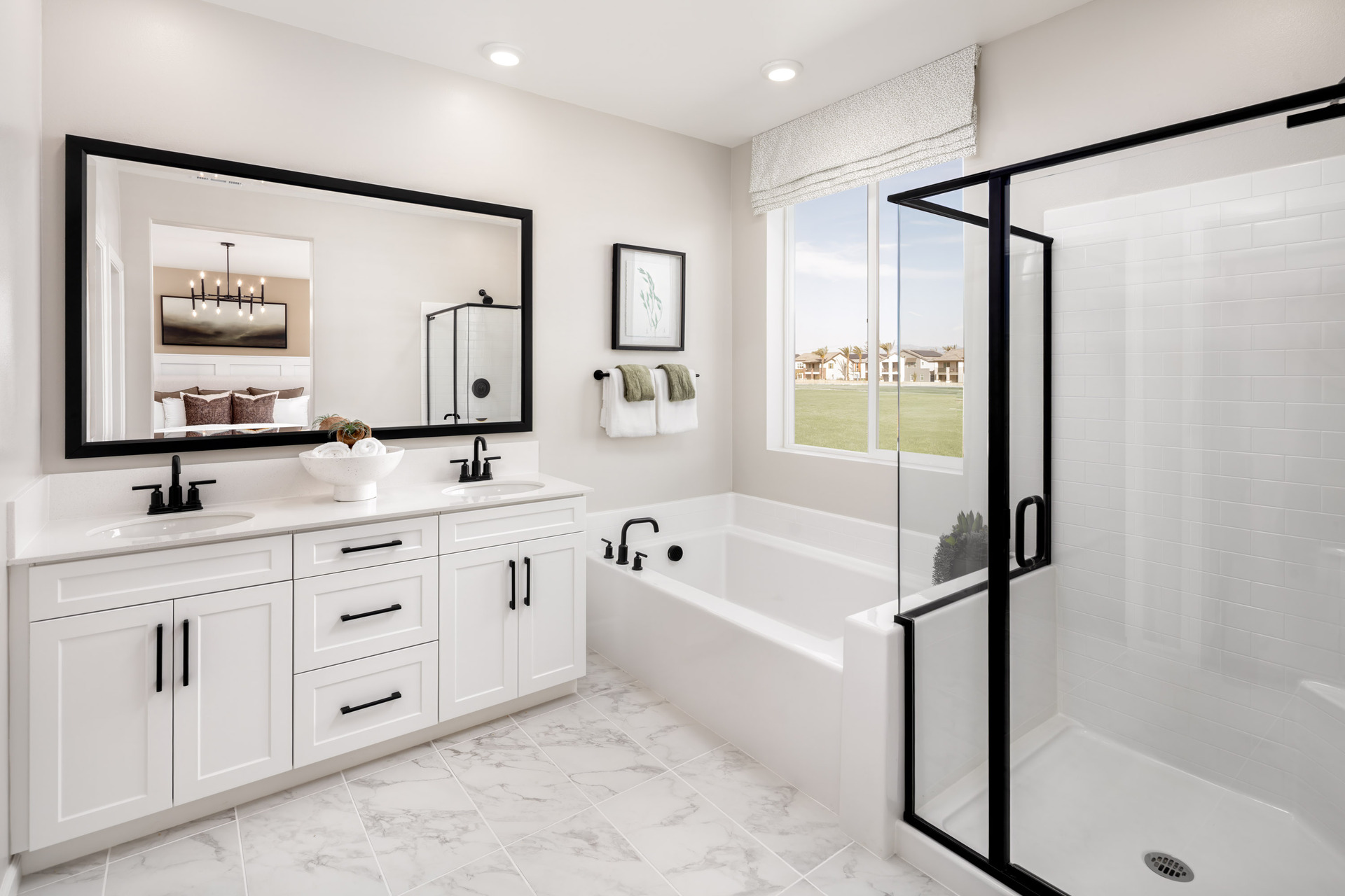 primary bathroom with white cabinets and large window